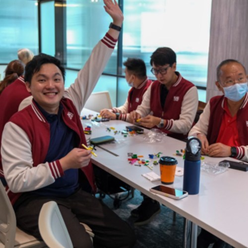 Participant celebrating with hand raised during a BNI Matrix LEGO SERIOUS PLAY workshop